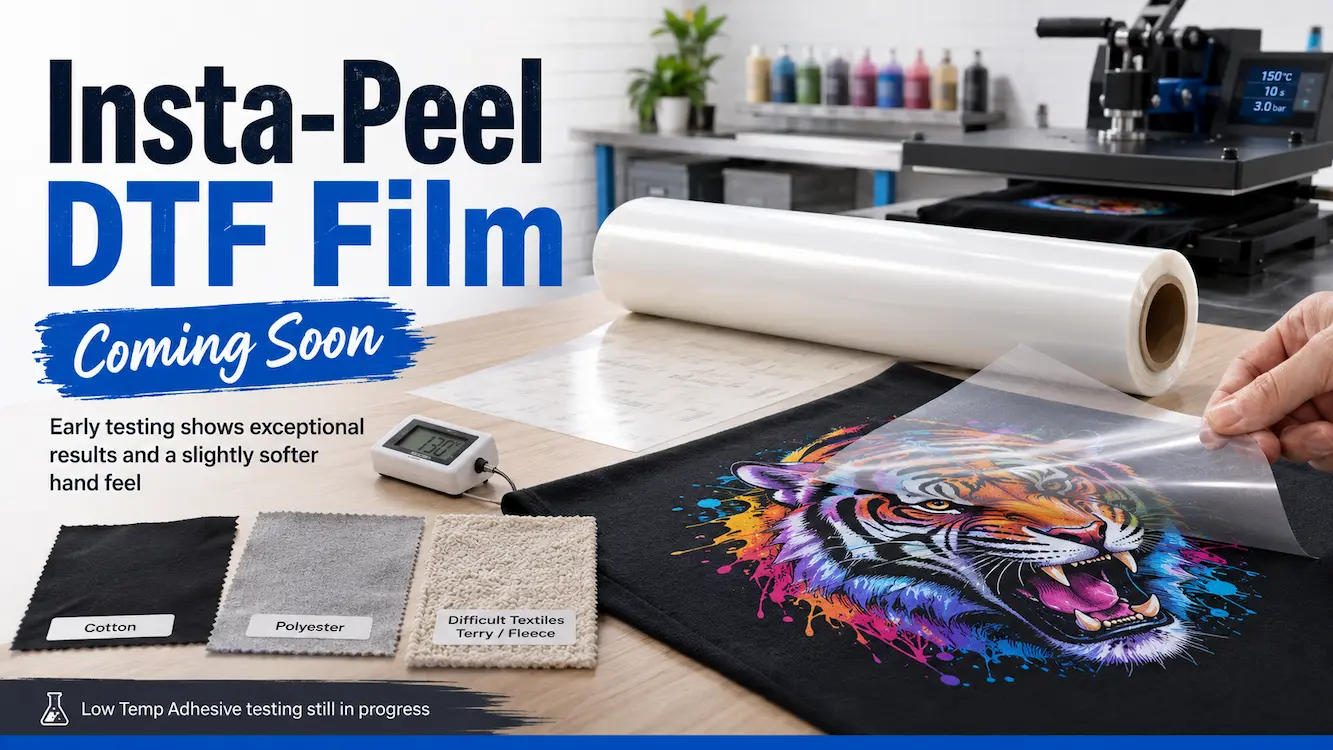 Insta-Peel DTF film roll being tested with a colourful transfer peeled from black fabric in a professional print shop.