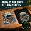 Astronaut design on clear DTF film beside a matching black T-shirt, with an inset illustrating the glow-in-the-dark effect.